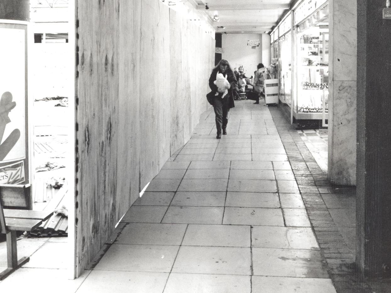 A shopper makes her way through the boarded up Seacroft Centre.