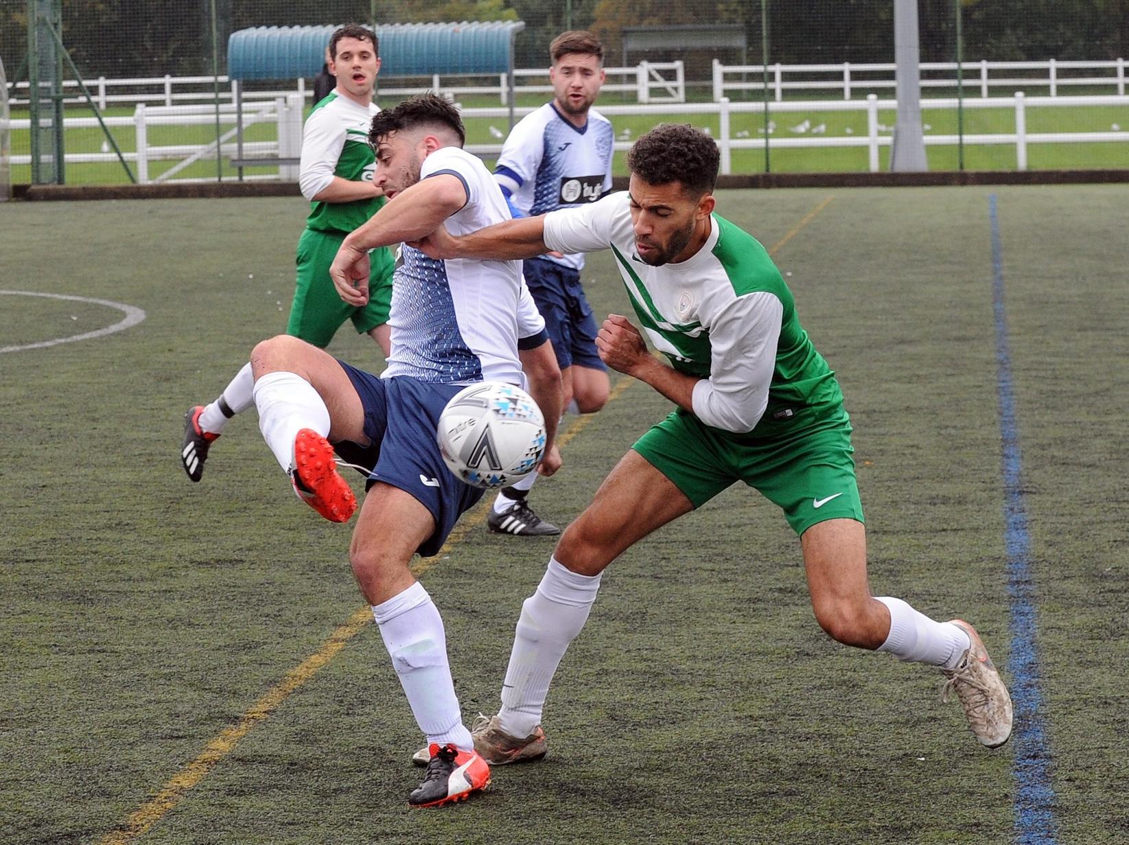 Ryan Hartley of Morley Town flicks the ball on under pressure from Tom McLeish of Trinity.