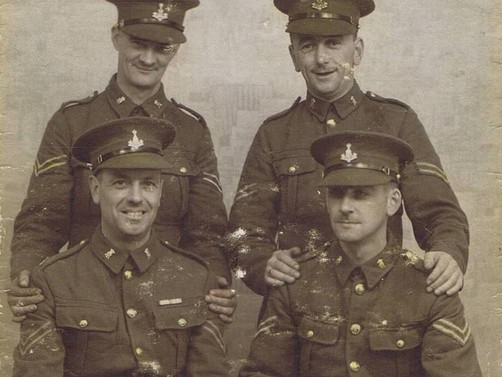 Studio photograph of four Green Howards Corporals, two standing an two seated. The photograph is captioned The "Four Legs" and written on the reverse is Ireland Sanfrey, St. Johns St. Bridlington? World War 1 but date and location not known