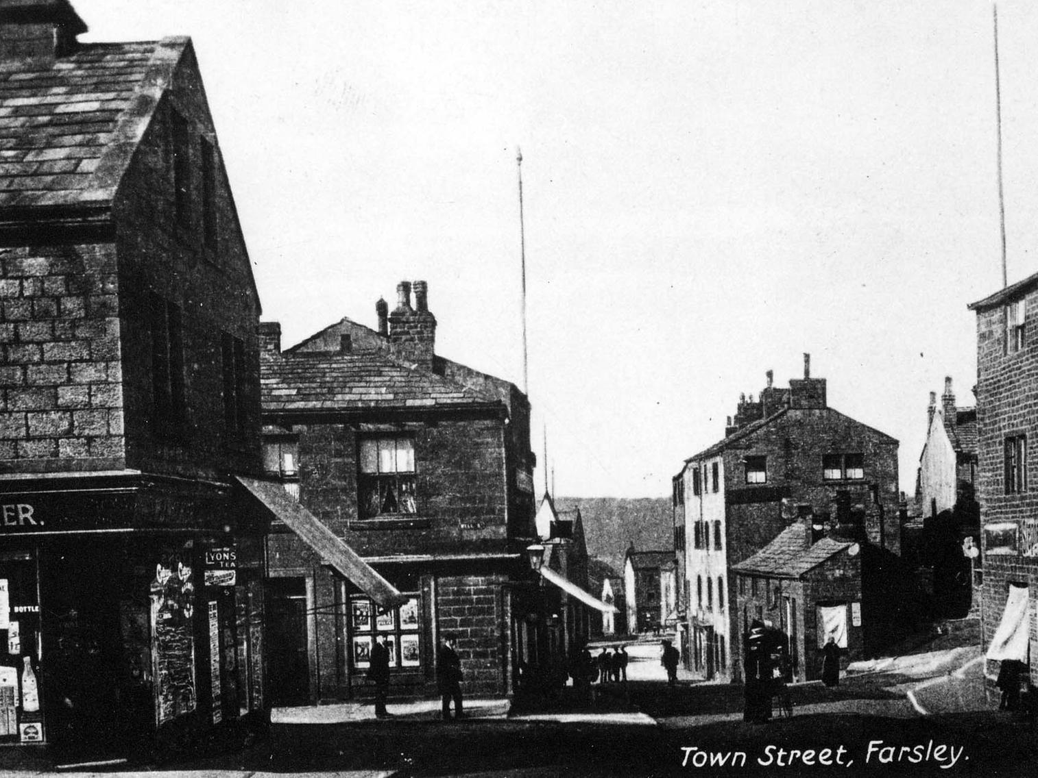 A view looking north along Farsley Town Street. On the left is W.J. Walker, grocer and beer retailer on Croft street. Road on the right is Gambles Hill.