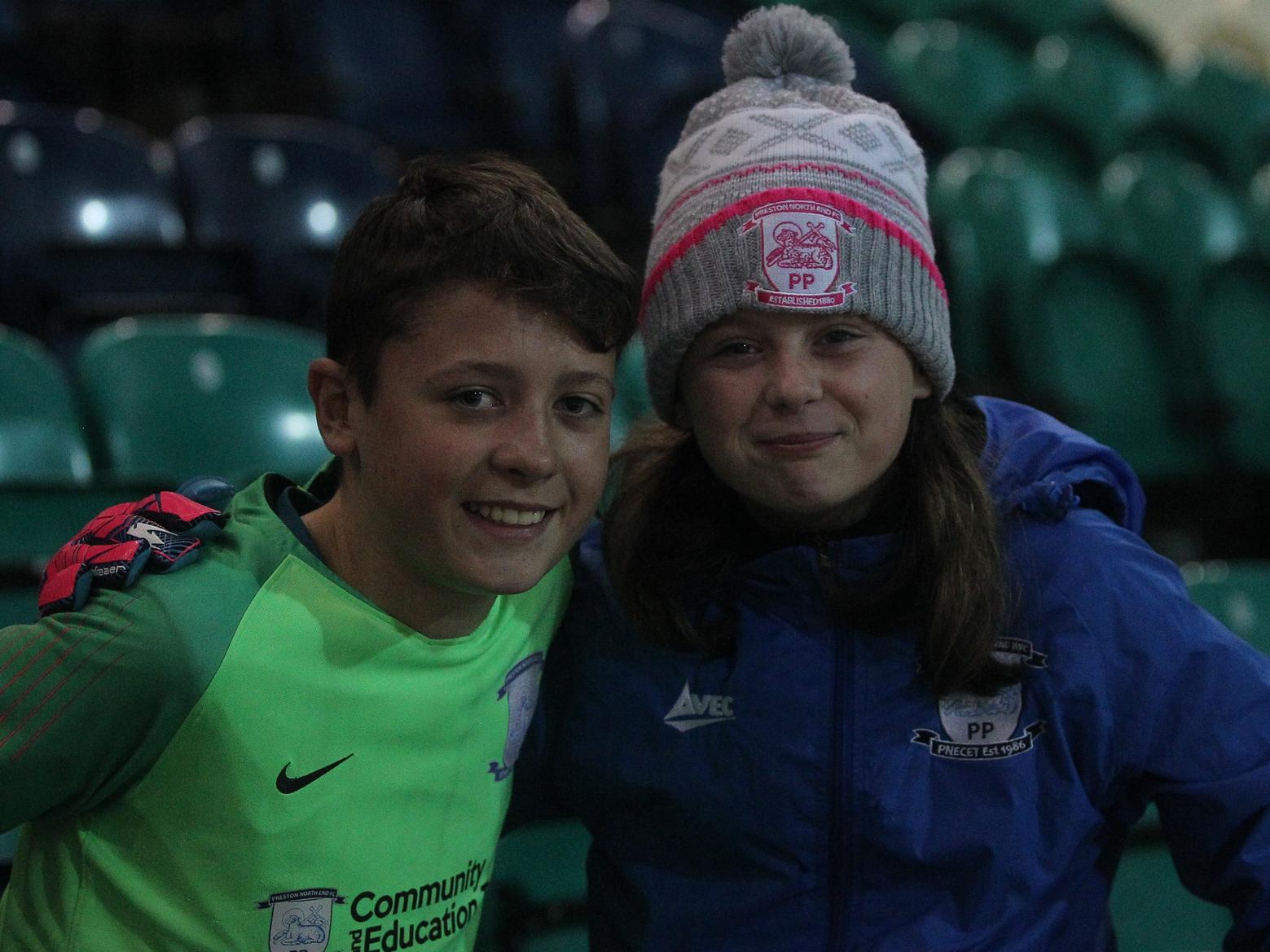 Two young fans smile despite the cold, with goalkeeper gloves favoured over the usual woolly ones.