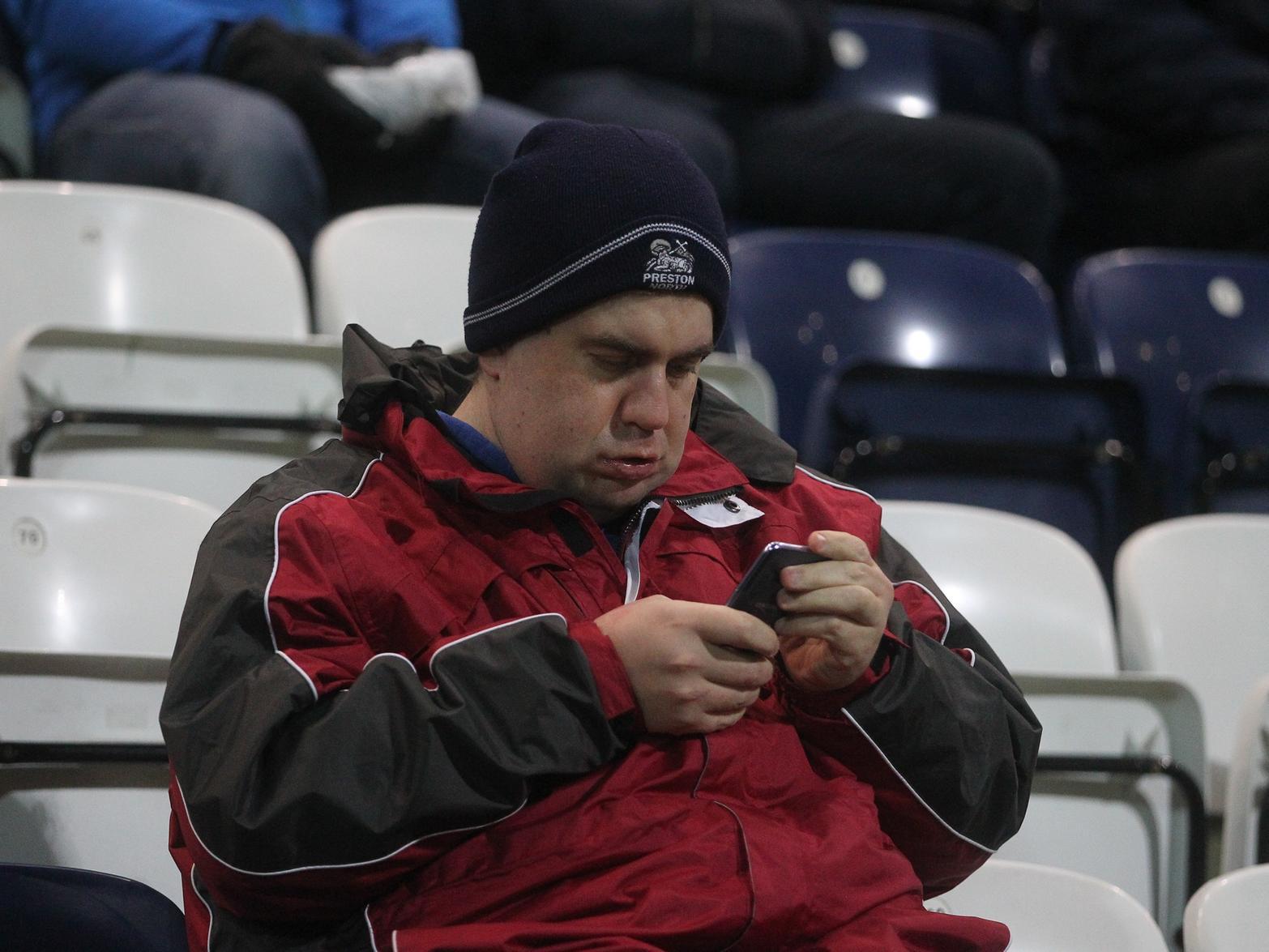 One fan checks their phone before the night's game.