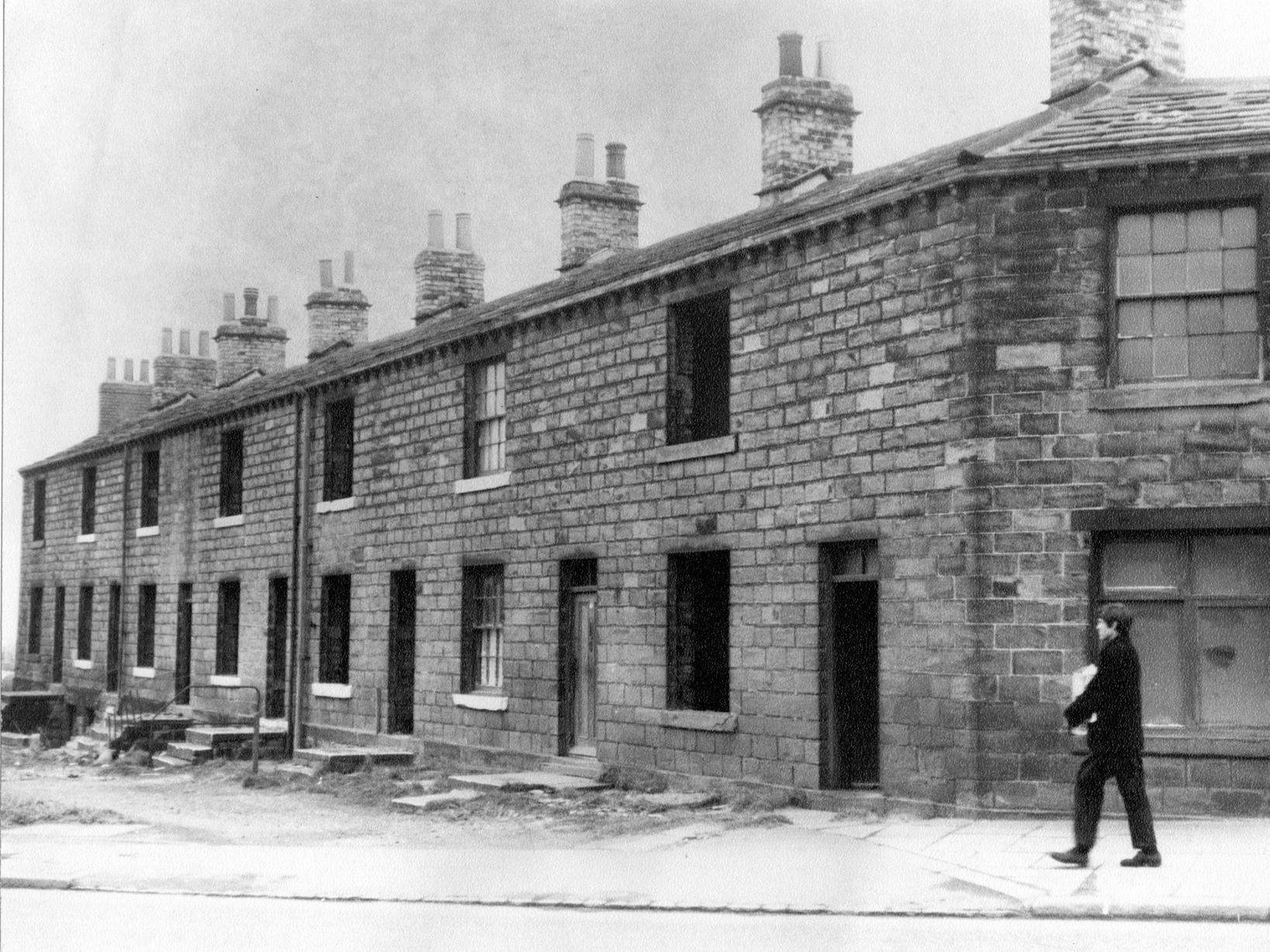 A view of derelict houses on Gelderd Road. House second from the right still has curtains to the windows and could still be occupied. A boy is walking along the road in the foreground.