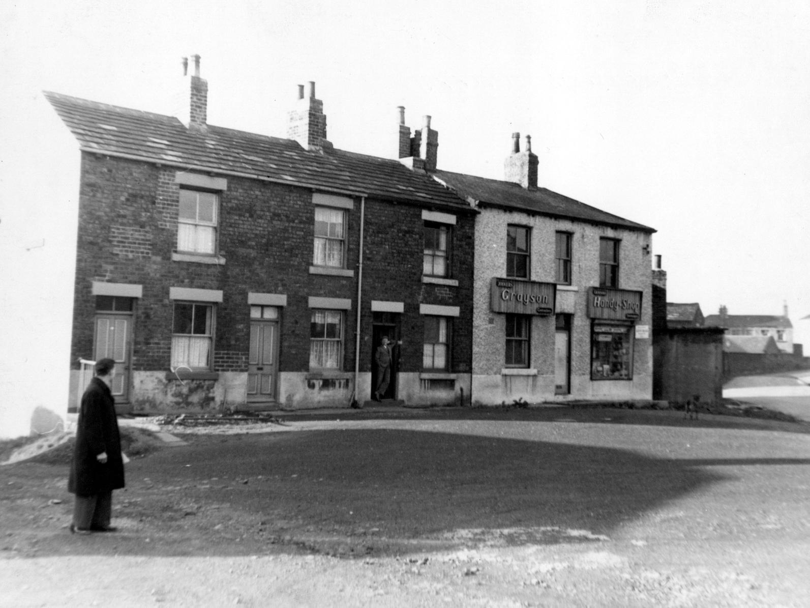 Town End at Gildersome, showing terraced houses and Grayson's Handy Shop in the double fronted end terrace. A man can be seen conversing with a man on the doorstep.
