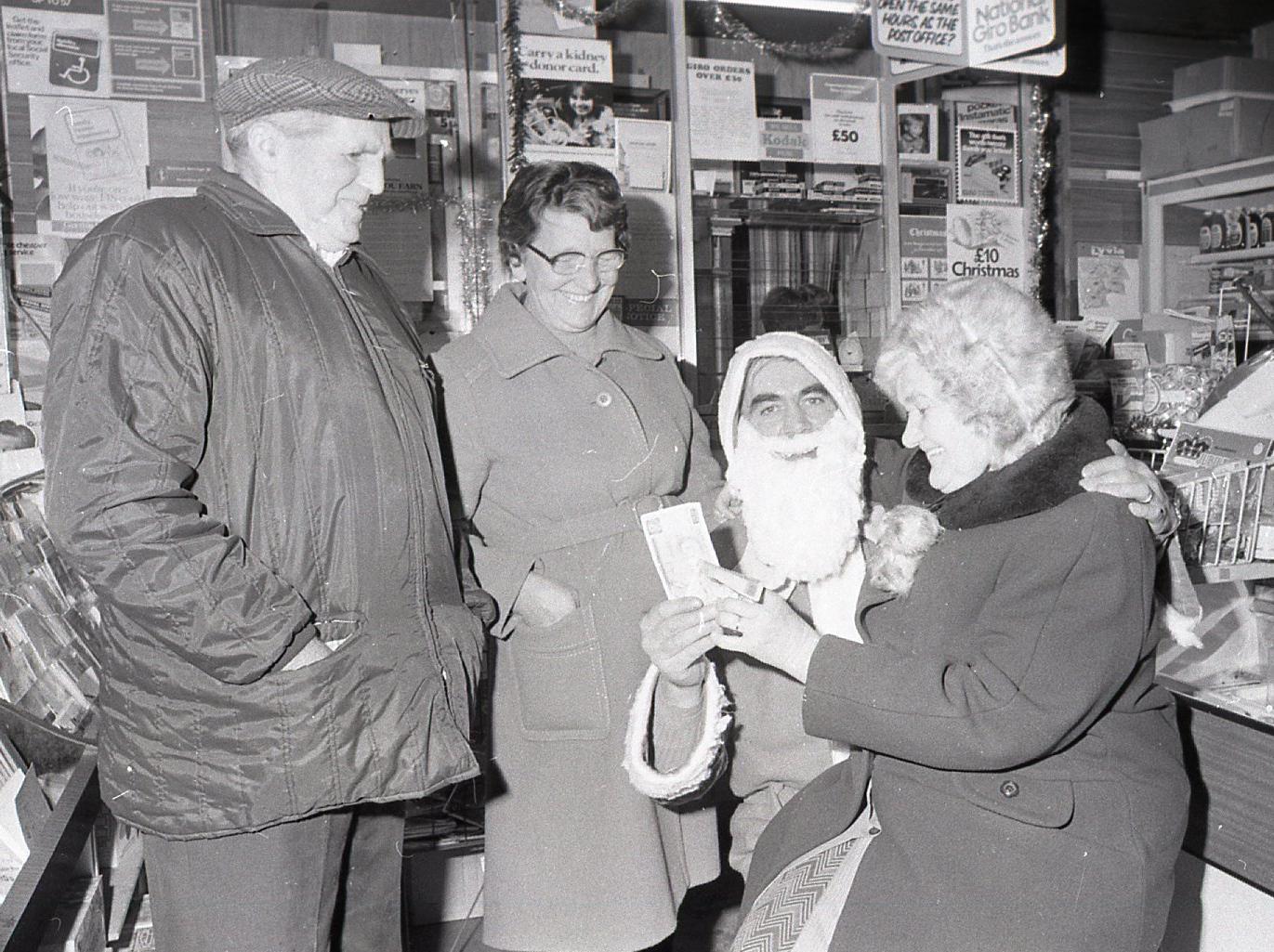 Seasonal cheer was the bright idea of sub-postmaster Bill Stuart at Catterall sub-post office - he appeared as Father Christmas when he handed over the 10 bonus to pensioners. Receiving her bonus is Mrs Doris Armstrong, of Garstang Road
