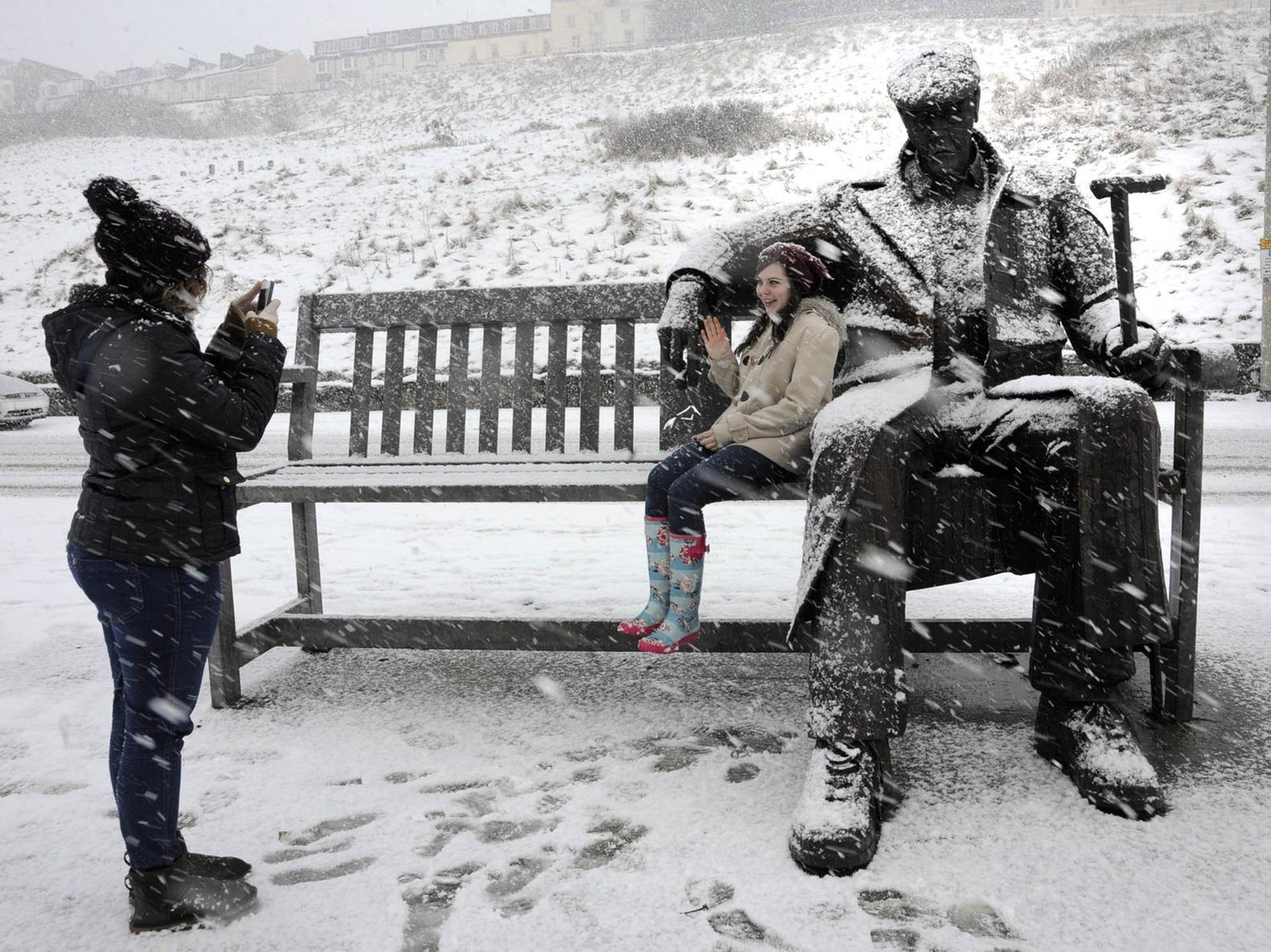 Amy Hunter, left, from Scarborough, takes photos of her friend Becca Hudless, sitting with a snow covered Freddie sculpture on the North Bay in 2013.