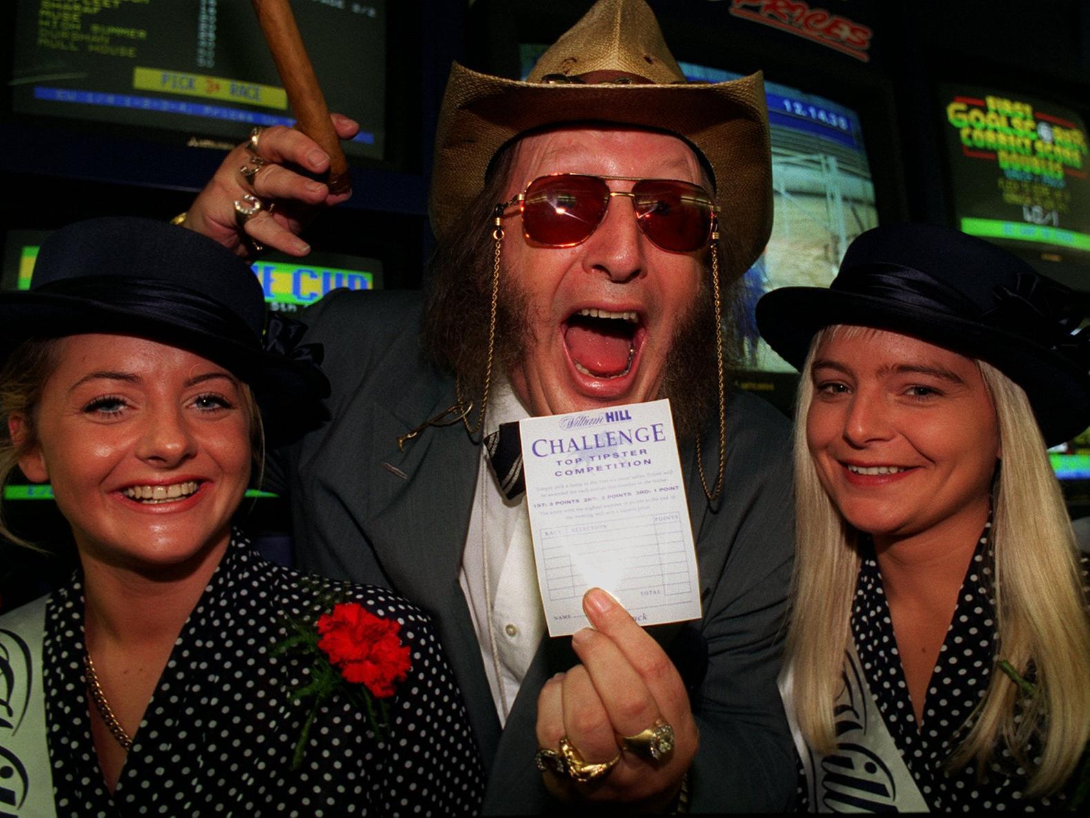 Samantha Allen (left) and Debra Wannan (right) with racing pundit John McCririck at Wiiliam Hill bookmakers on Vicar Lane where he placed a bet on behalf of Half and Half.