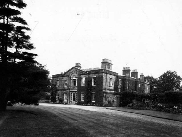 A view dating from August 1949 of the front entrance to Cookridge Hall, a stone built mansion partly covered in ivy. The site is an ancient one.