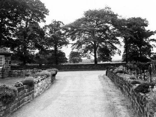 A view of Cookridge Lane, looking east from Smithy Lane in July 1952.Smithy Farm is the building on the left. The roads are bounded by stone walls.