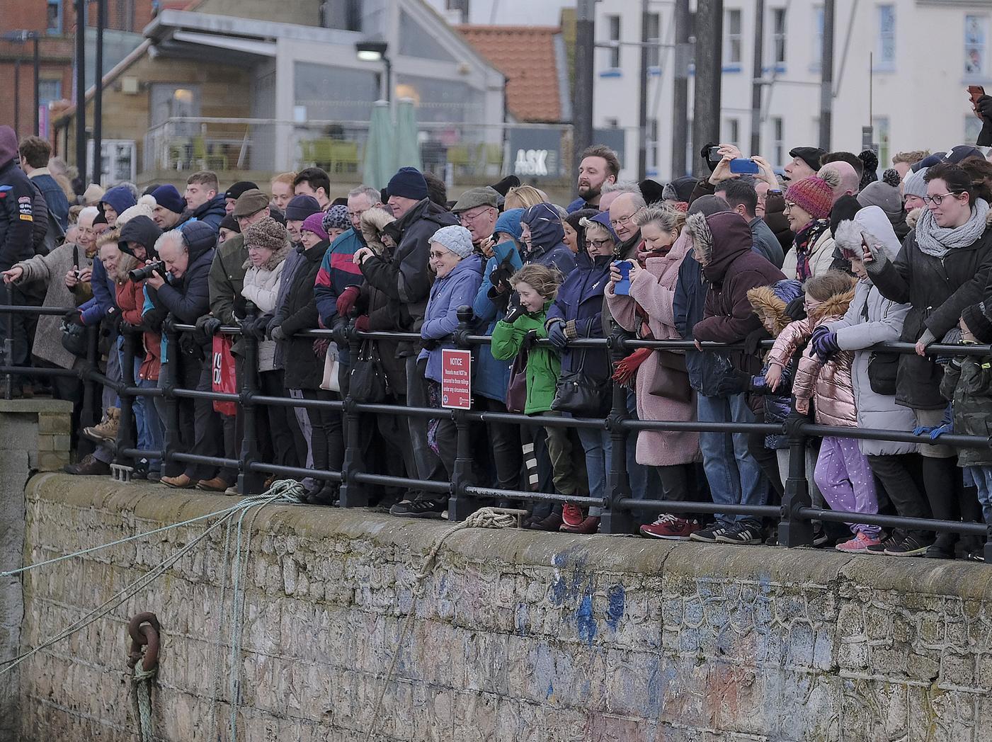 Spectators crowd along the harbour side.