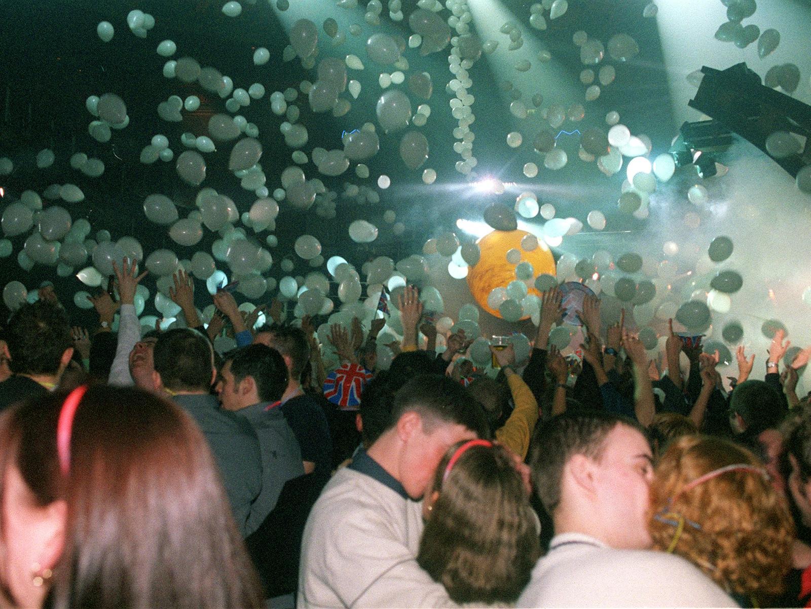 Couples embrace on the dance floor as hundreds of balloons are released.