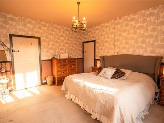 One of the five bedrooms, a large double room with space for a range of furniture and feature doors.