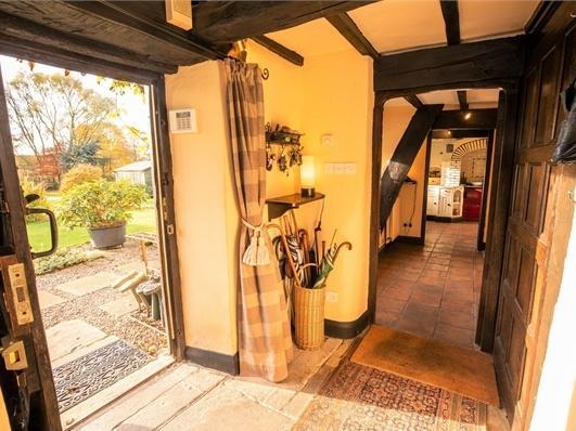 The hallway features Yorkshire stone flooring and exposed beams. Door leading to the outside garden.