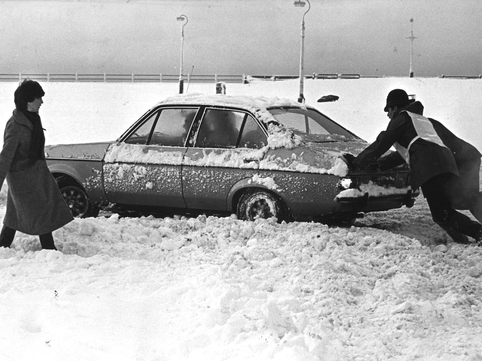 A car is pushed out of the snow on the promenade