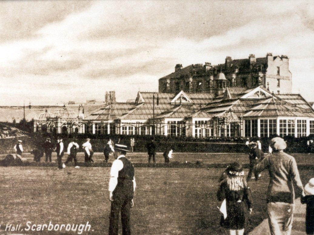 On the site of the current Alexandra Bowls Club stood the Floral Hall, and in front people can be seen enjoying the greens.