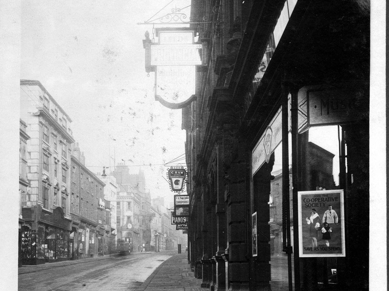 Albion Street. On the right is part of Leeds Industrial Co-operative Society. The company had two blocks of property, one on each side of the road. Posters in the window advise 'Join the Co-operative Society - Save as you spend'.