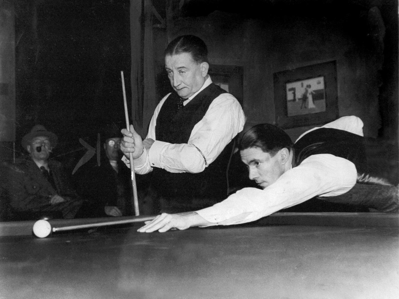 Famous billiards player Melbourne Inman watches his opponent, Sydney Smith, making a break in the Gold Cup sealed handicap billiard competition in Leeds.