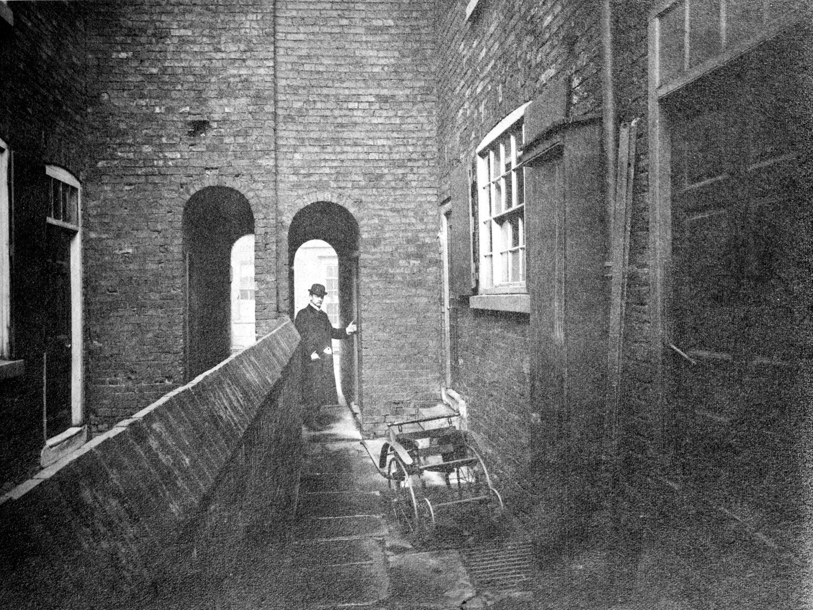 A view of Dawson's Court, which leads off George Street. It shows a narrow alleyway with a man in smart attire standing in entrance.