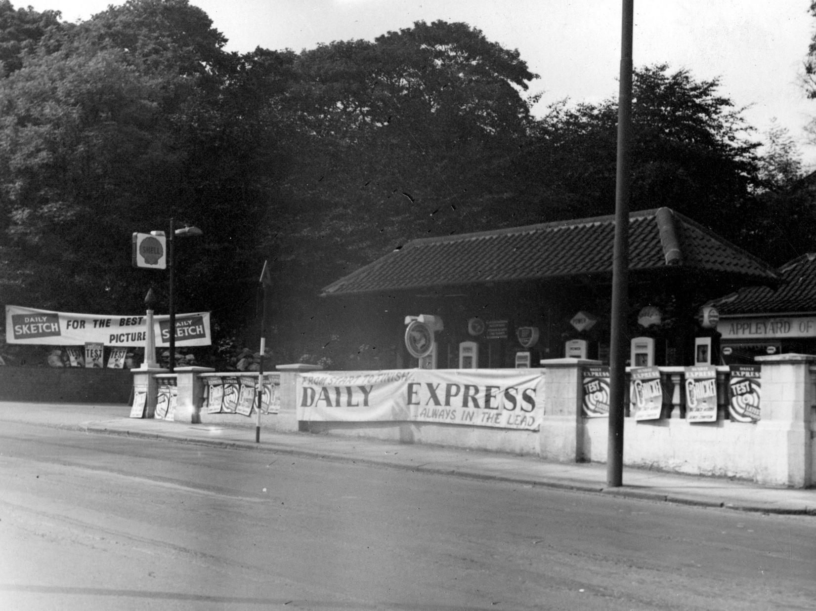 Petrol station Appleyard of Leeds at Headingley Lane. Banners advertising The Daily Express and The Daily Sketch are displayed on the wall in front of and to the side of the garage.