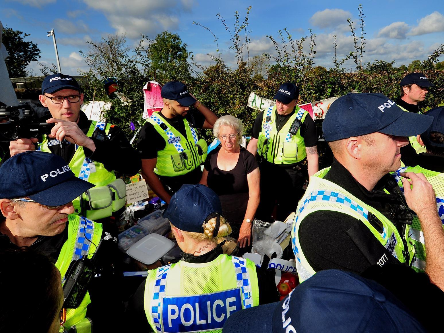 Police move tea lady Jackie Brookes from her table, to enable the police to remove a tower built on the site.