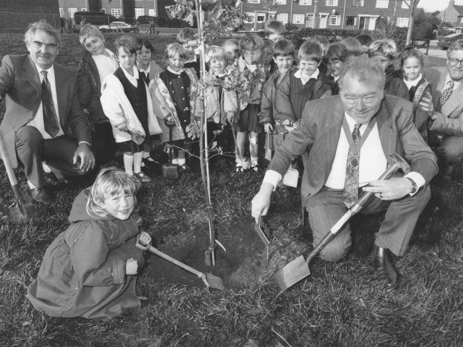 Pictured is chairman of Hunmanby Parish Council Pat Dowey, front right, adding the finishing touches to a tree planting at Hunmanby Country Primary School, assisted by five year old pupil Lauren Dobson, and watched by other pupils and teachers from the school. Photo taken in November 1994.
