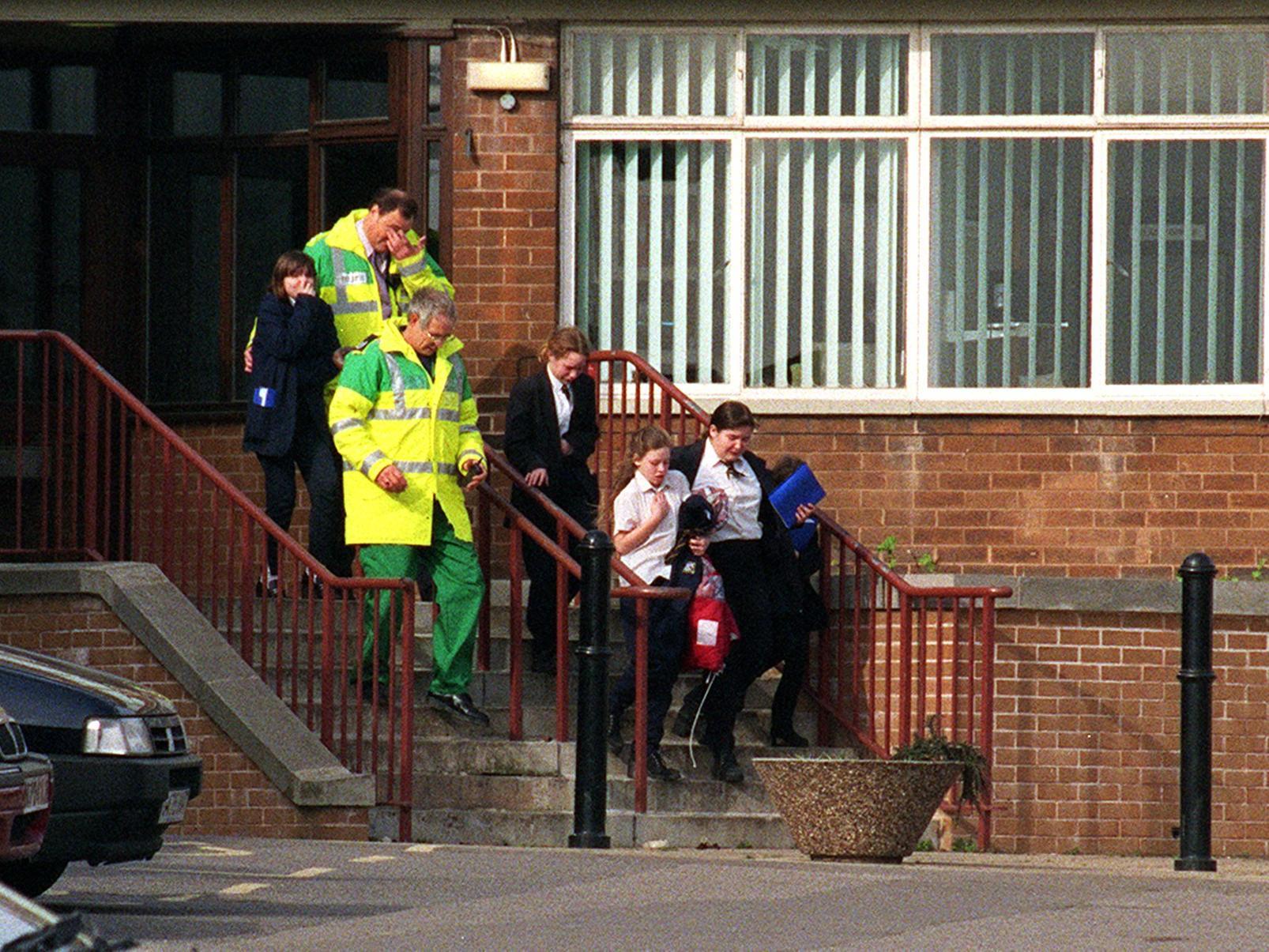 Pupils from West Leeds High School are led away by ambulance men after the roof of their school was blown off in high winds.