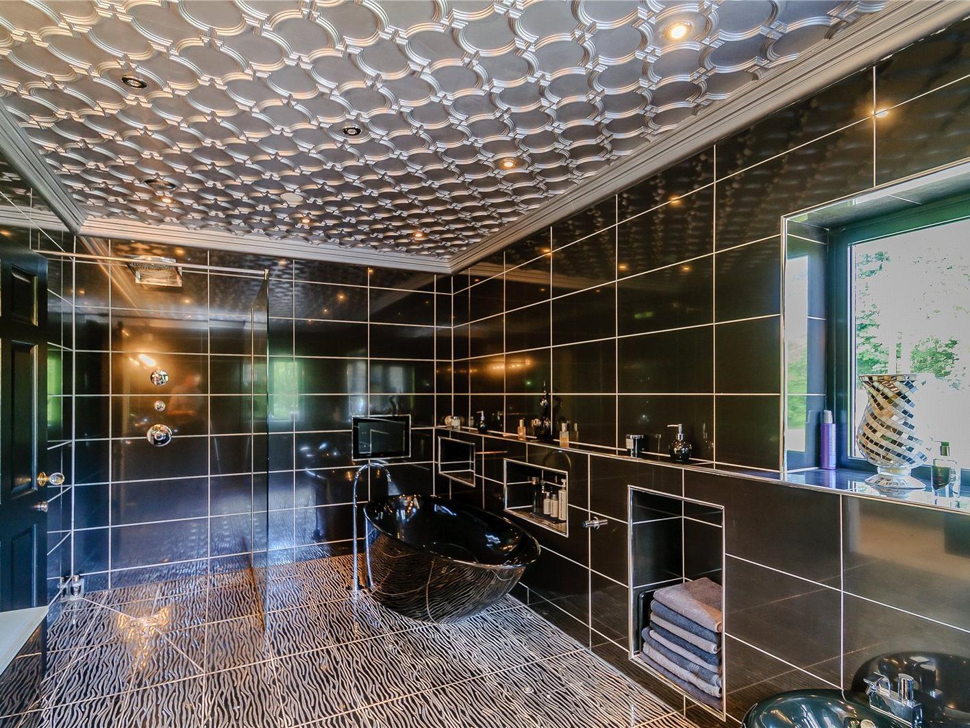 The master bedroom has an en-suite bathroom with a full suite, including an oval shape stand-alone bath with aqua TV and wet room style shower behind glazed screens.