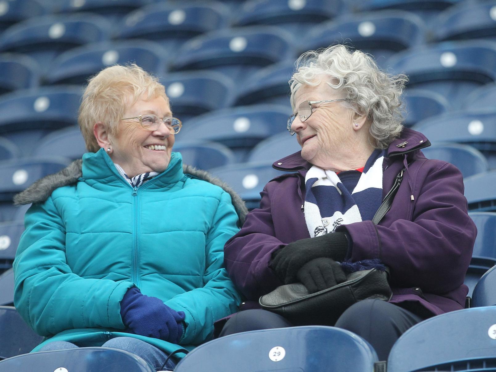 Two Preston fans share a smiling glance to each other, wrapped up ready for the contest.