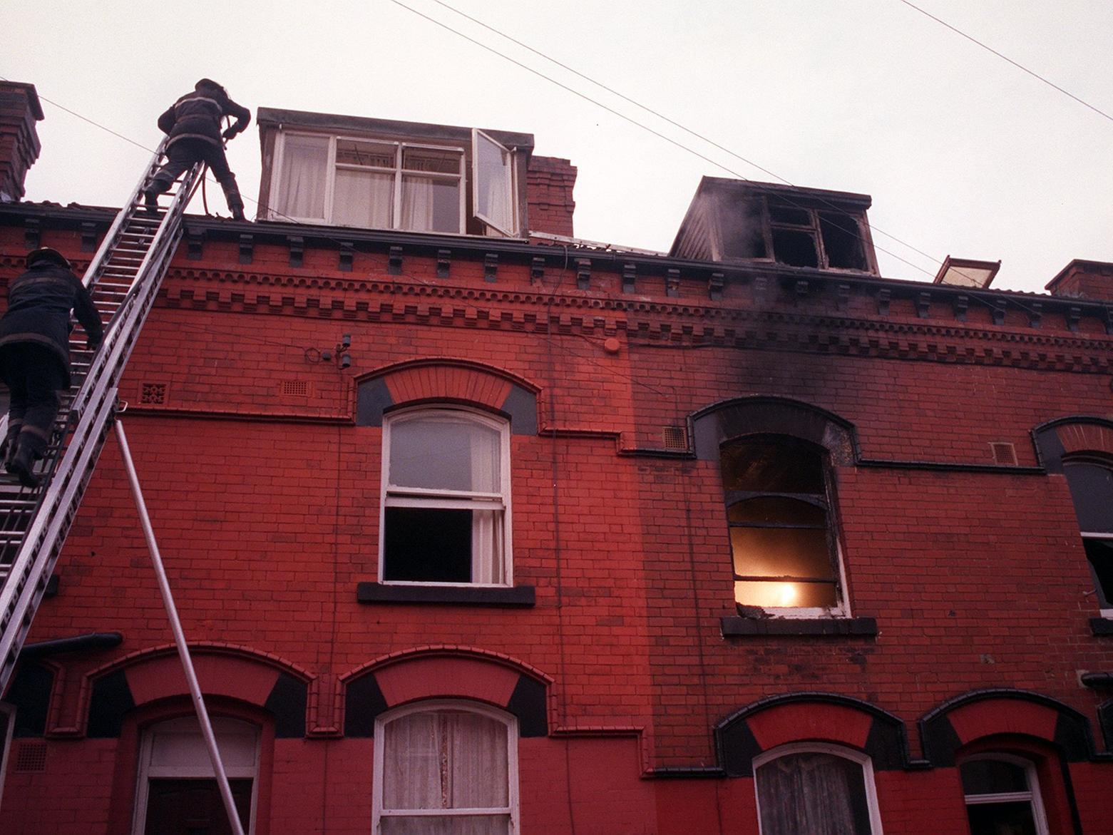 Firefighters clamber on to the roof of a house in Harehills from where a woman was rescued after a blaze.