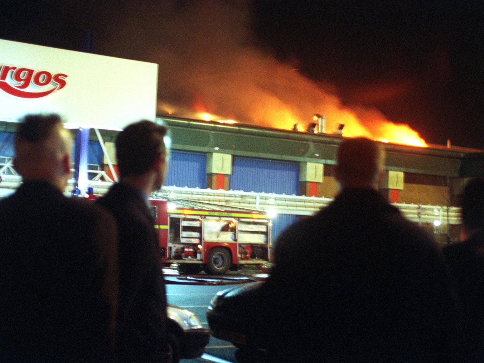 People gather to look at the fire engulfing the Argos Superstore at the Crown Point Retail Park in Leeds.