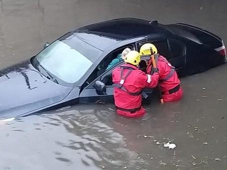A motorist being rescued from severe flooding.