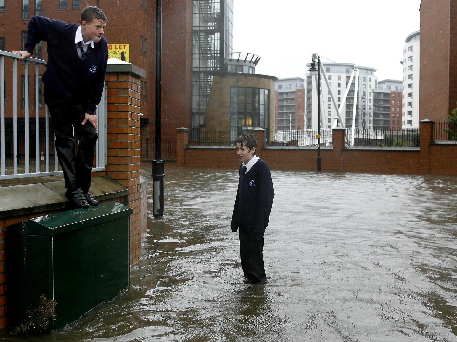 Schoolchildren run through flood waters after the banks of the River Aire in Leeds city centre were broken by heavy rain.