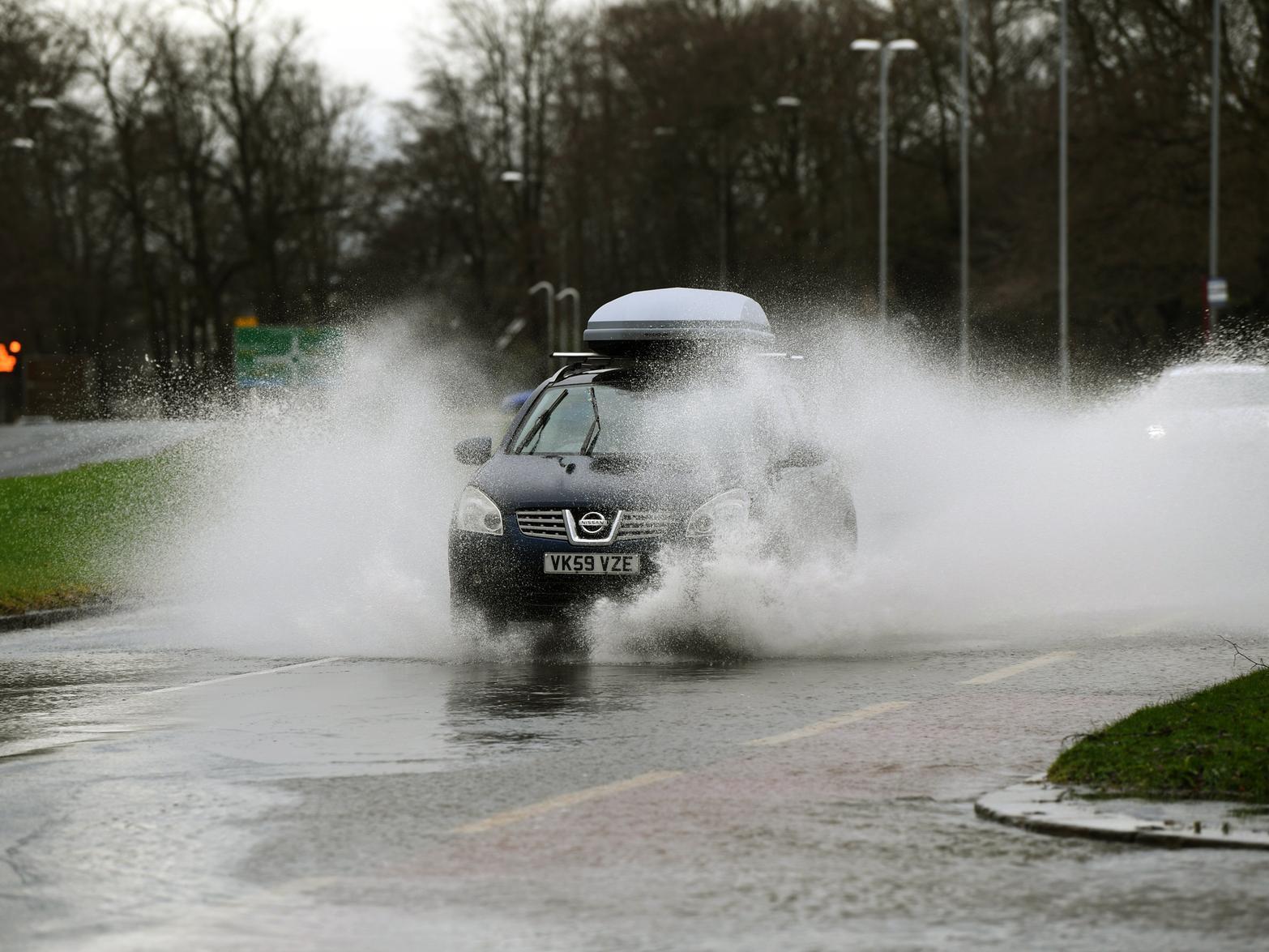 A car drives through flood water on Otley Road.