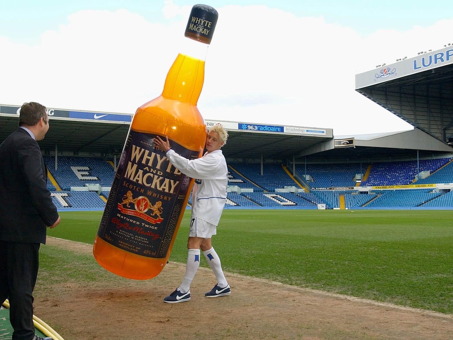 Striker Alan Smith carries a large replica bottle of the club's new multi-million pound sponsors Whyte and Mackay whisky from the Elland Road pitch,