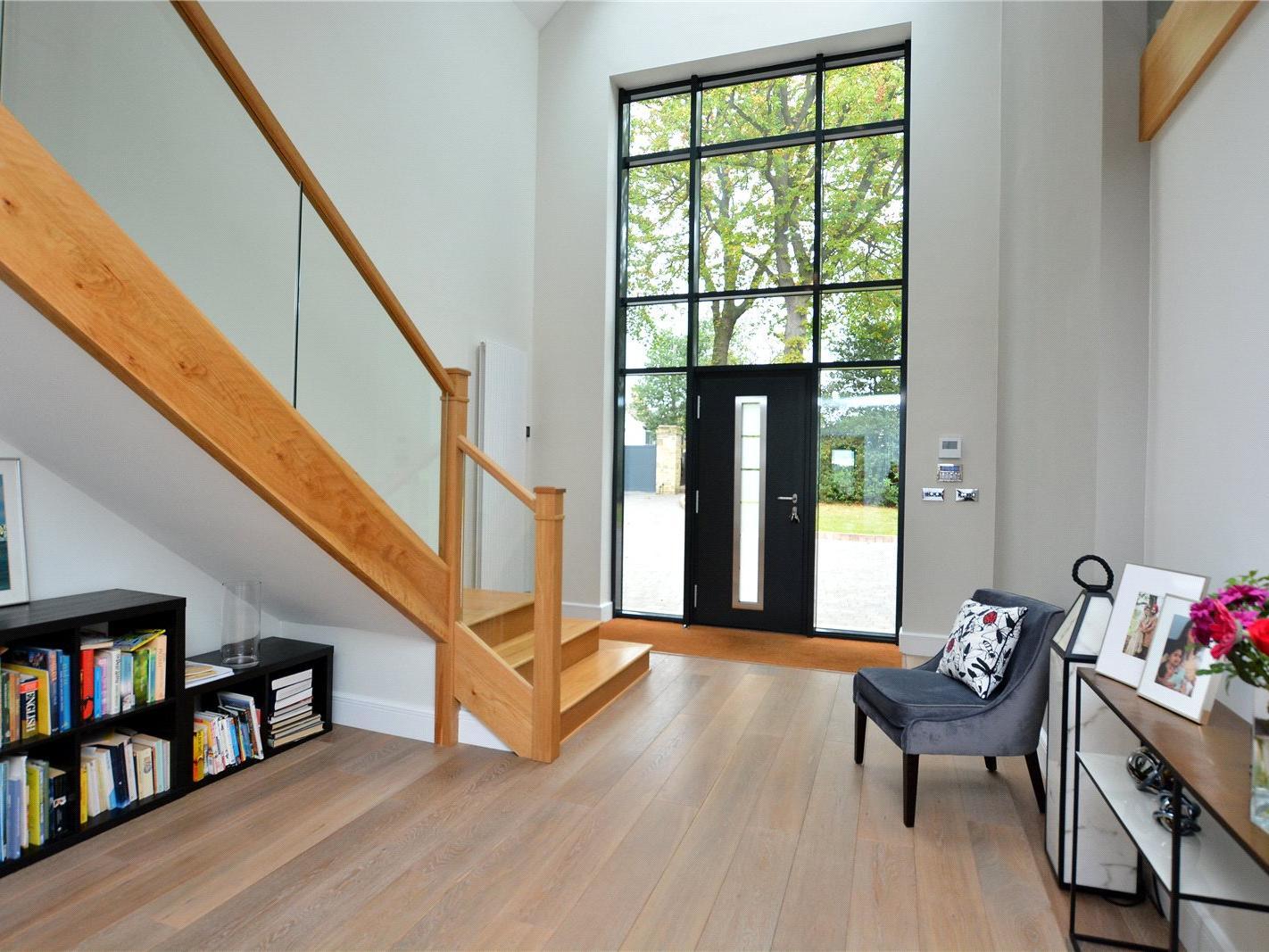 The triple height hallway features floor to ceiling windows and solid oak flooring.