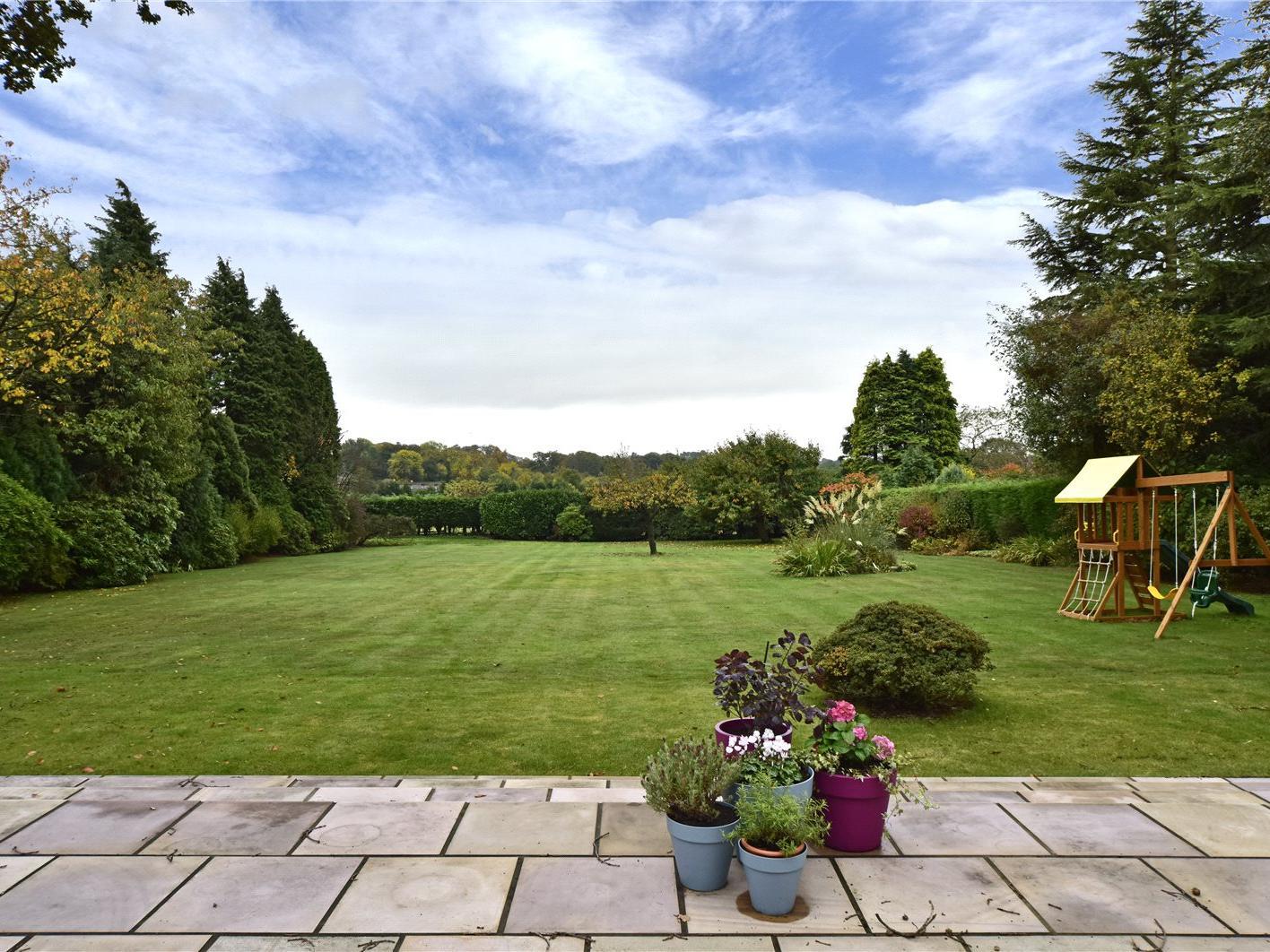 The rear one-acre garden is faced with a large paved terrace and large lawns.
