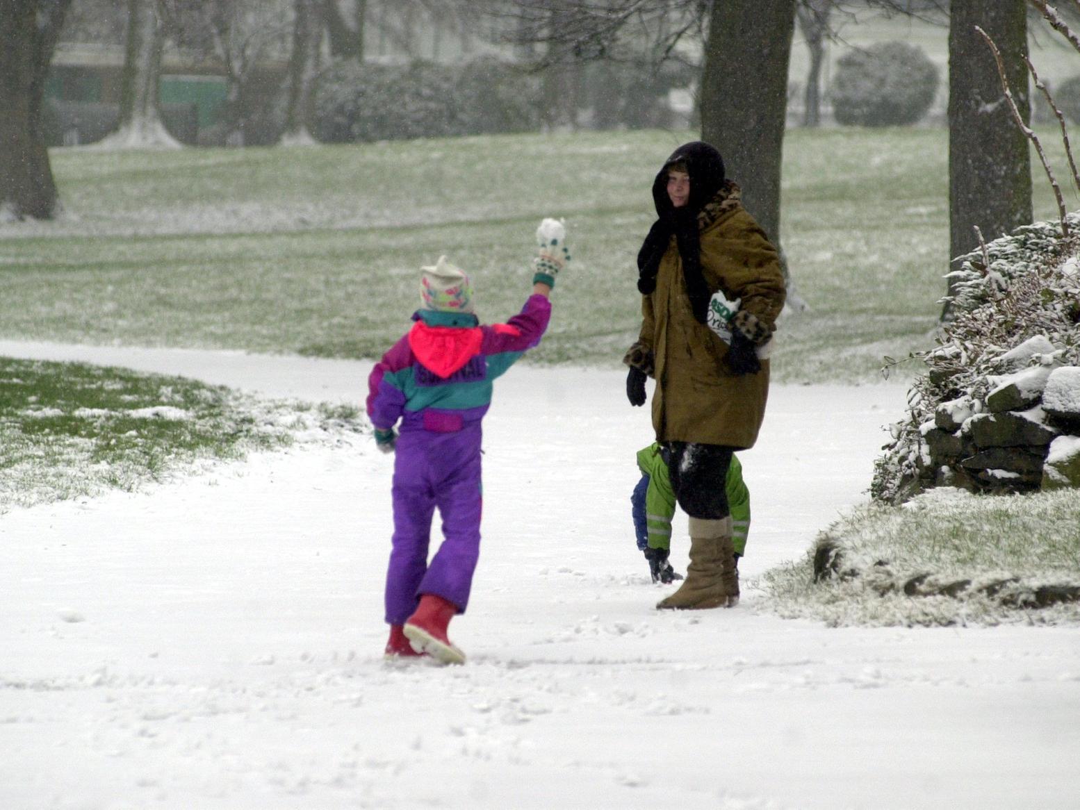 A youngster dares to throw a snowball at his mum while walking through the grounds of Kirkstall Abbey.