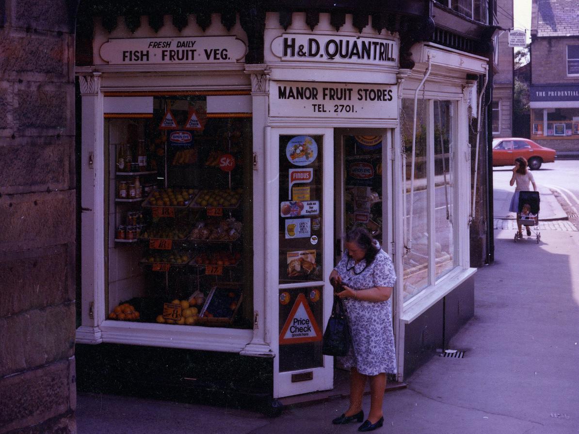 Clapgate showing H&D Quantrill's greengrocers store. On the right is Manor Square with the Prudential Assurance Company just visible. To the left of Quantrill's is a passageway leading to Bay Horse Court.