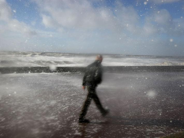 A man braves the sea spray as waves blow over the sea wall on the seafront at Blackpool (Photo by Christopher Furlong/Getty Images)