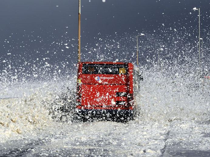 A bus drives through a blizzard of foam as gales and large waves hit the seafront at Cleveleys, near Blackpool, as the remnants of Hurricane Gonzalo blew into Britain, causing rush-hour travel misery