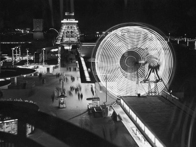 Illuminated rides at The Pleasure Beach in Blackpool, including a ferris wheel and the Big Dipper, 10th September 1955.