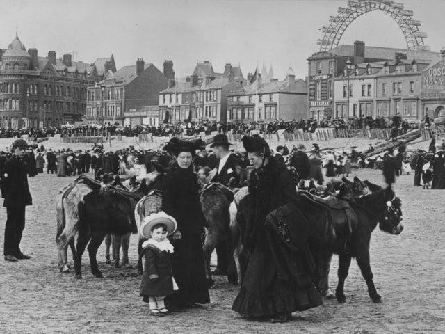 A family preparing to take a donkey ride on Blackpool beach, 1903. Lancashire.