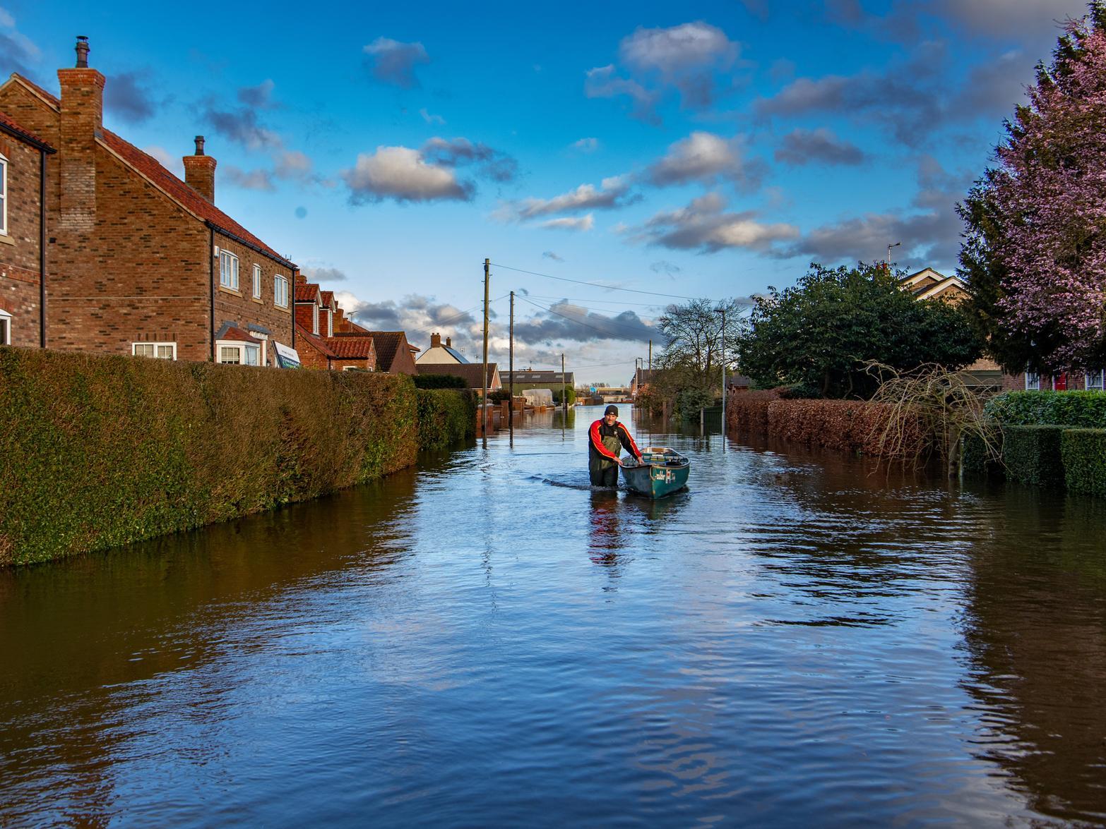 A man pushes a boat in East Cowick, East Yorkshire, as floodwater continues to affect many properties in the village. Picture: James Hardisty