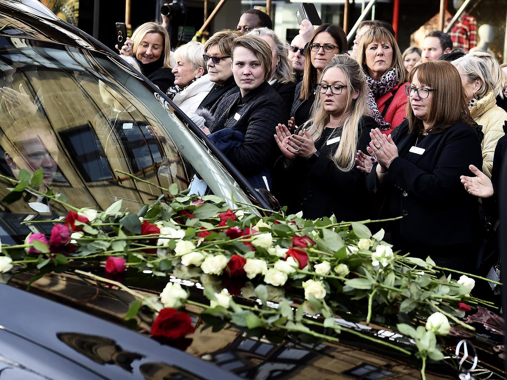 Mourners applauded while many placed roses on the front of the hearse.
