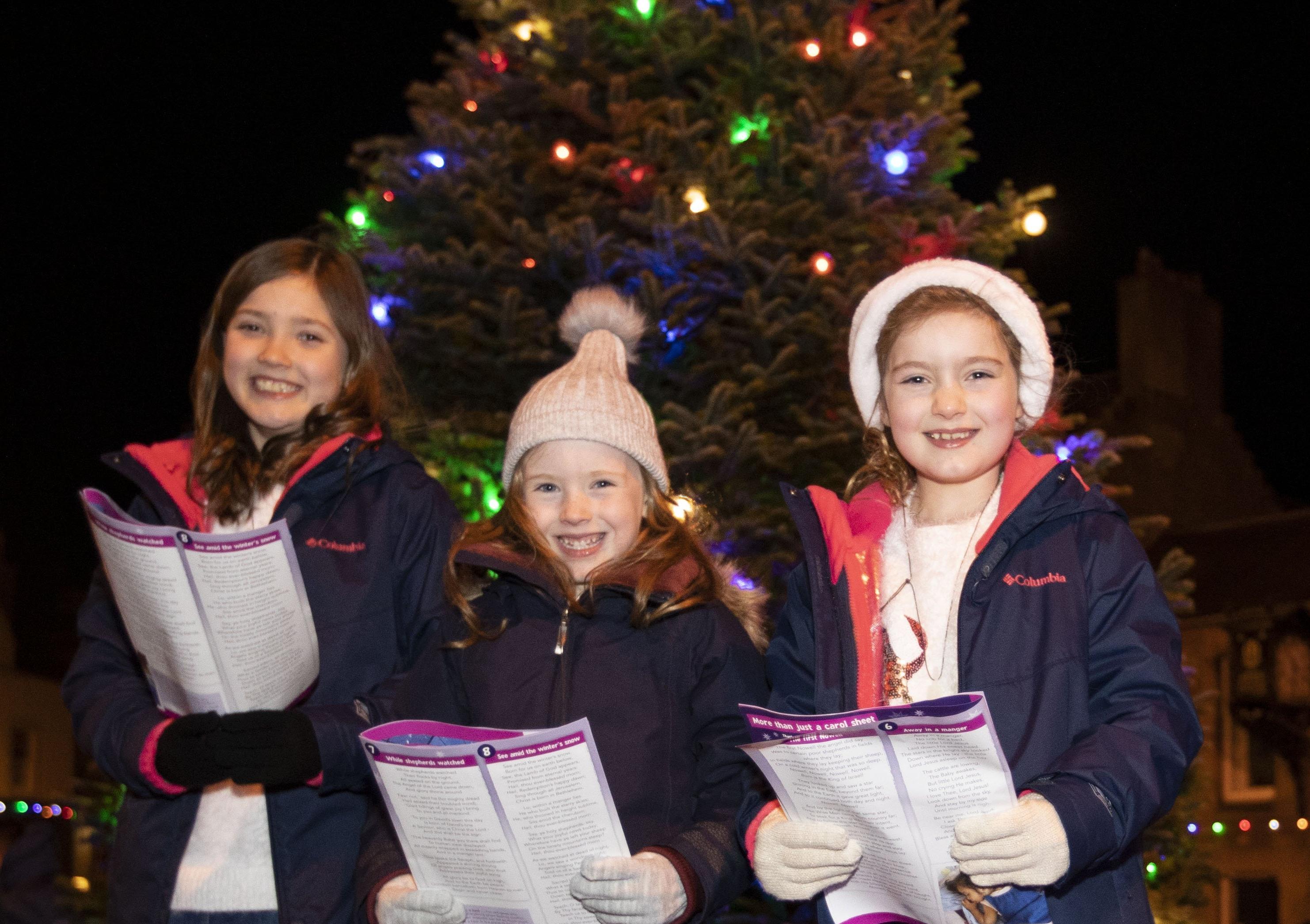Friends sing carols around the Christmas tree in Melrose.