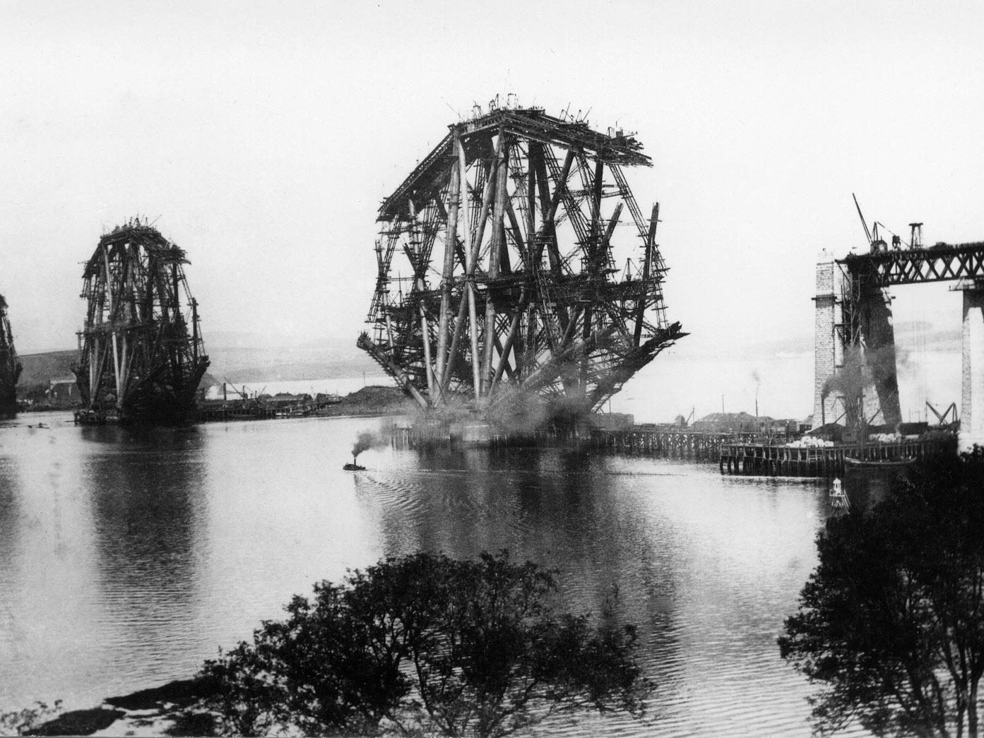 A view of the Forth Bridge taken in the mid-1880s, shows the construction of the main cantilever structures which are supported by granite piers.