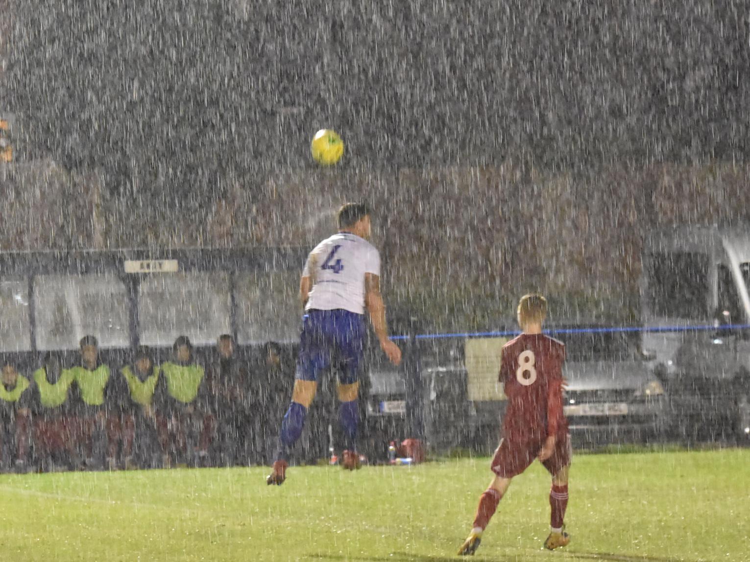 Nathan Cooper heads the ball away in torrential rain.