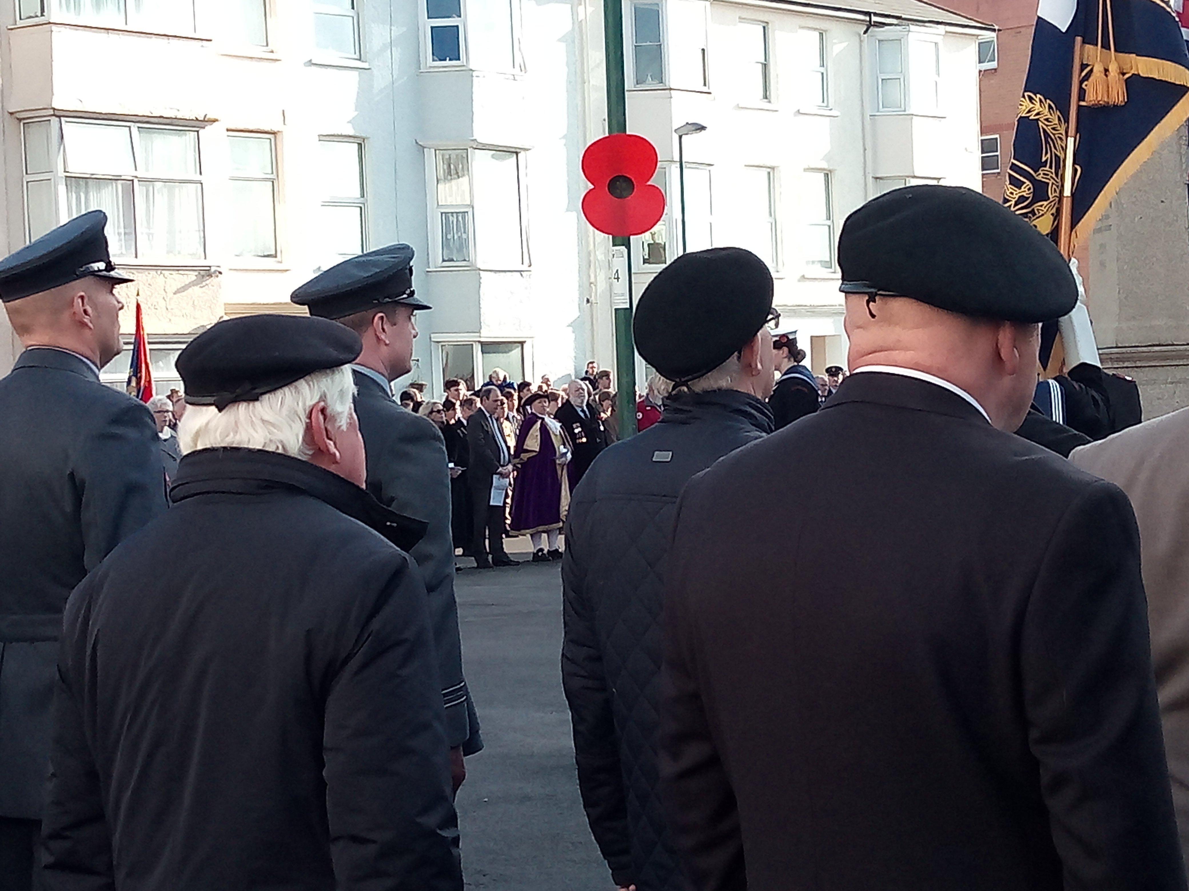 Servicemen and veterans on parade in front of a poppy