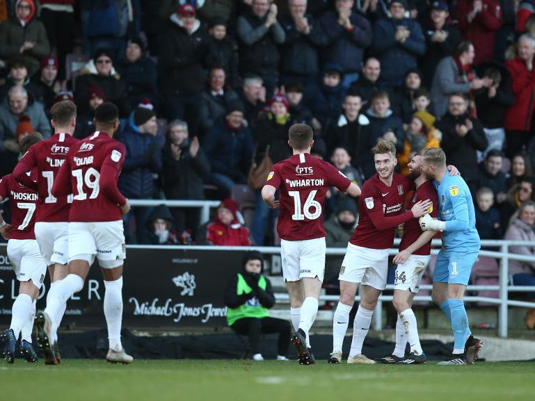 Cobblers players run over to celebrate with Paul Anderson after the midfielder's opening goal against Morecambe. Pictures: Pete Norton